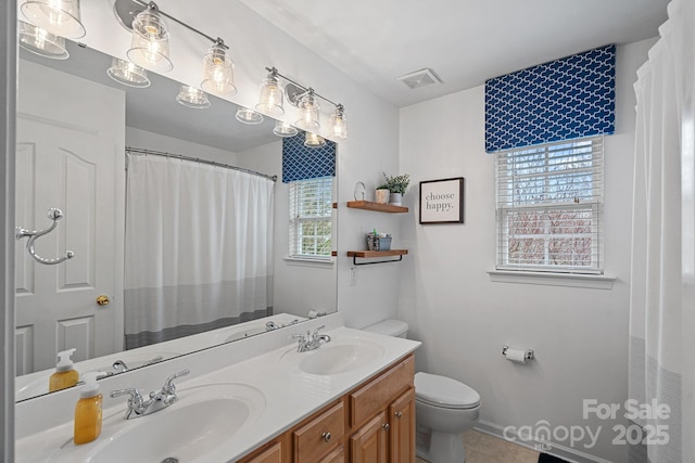 bathroom featuring visible vents, double vanity, a sink, and toilet