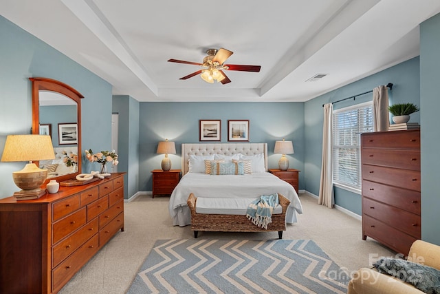 bedroom with light carpet, a tray ceiling, visible vents, and baseboards