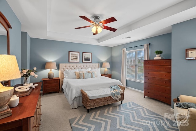 bedroom featuring ceiling fan, visible vents, baseboards, carpet, and a raised ceiling