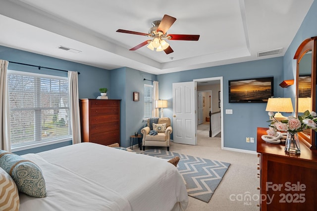 bedroom featuring carpet floors, a tray ceiling, visible vents, and baseboards