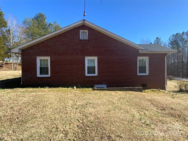 view of side of property featuring brick siding, crawl space, and a lawn