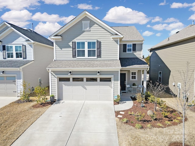 traditional-style home featuring covered porch, concrete driveway, a shingled roof, and a garage