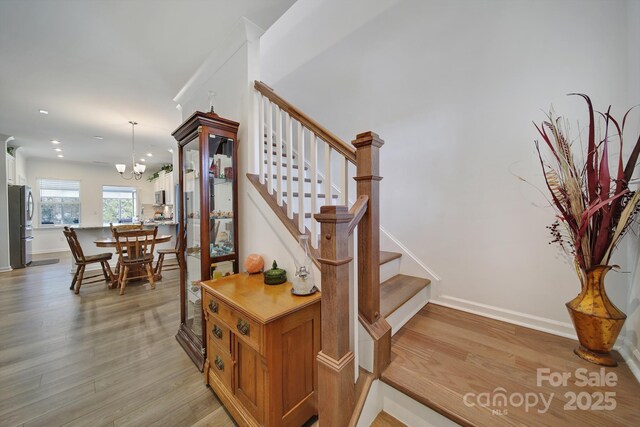 stairs with a notable chandelier, baseboards, and wood finished floors