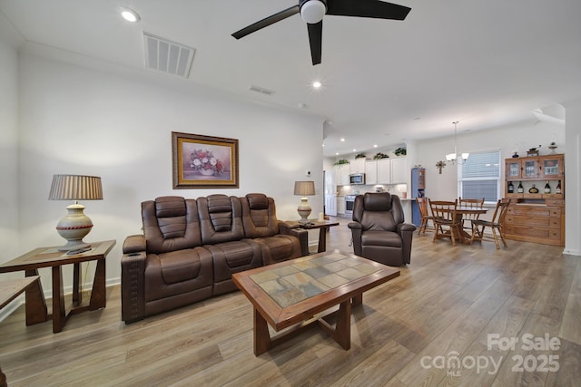 living room featuring ceiling fan with notable chandelier, recessed lighting, visible vents, and light wood-style floors