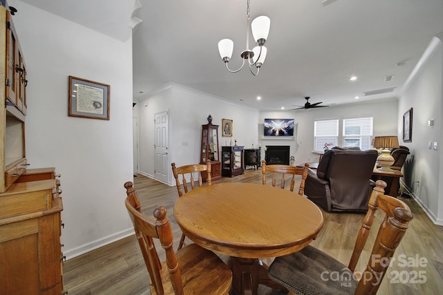 dining room featuring a fireplace, baseboards, dark wood finished floors, and ceiling fan with notable chandelier