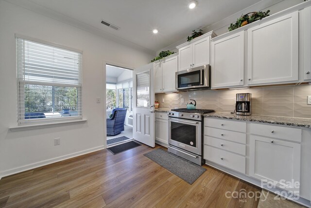 kitchen featuring visible vents, white cabinetry, appliances with stainless steel finishes, light wood-type flooring, and backsplash