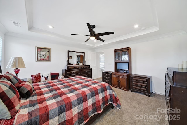 bedroom with light carpet, visible vents, ceiling fan, a tray ceiling, and crown molding