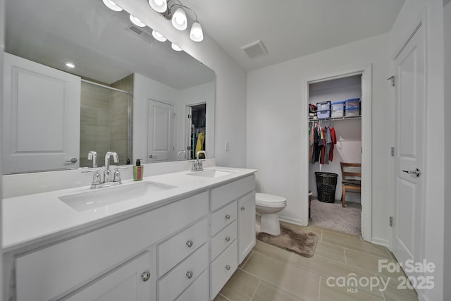 full bathroom with double vanity, visible vents, a walk in closet, and a sink