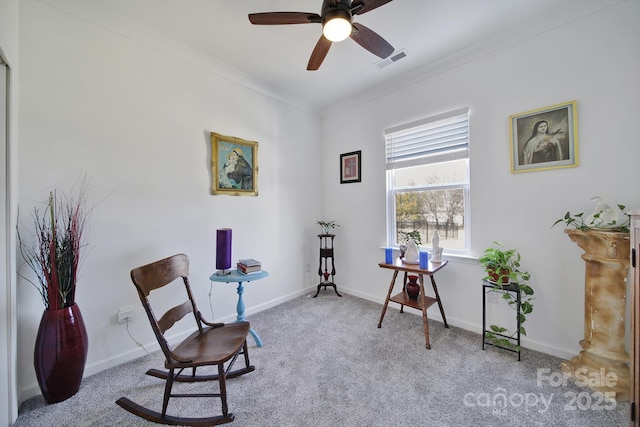 living area featuring baseboards, visible vents, a ceiling fan, light colored carpet, and crown molding