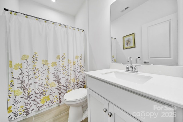 bathroom featuring toilet, visible vents, wood finished floors, and vanity