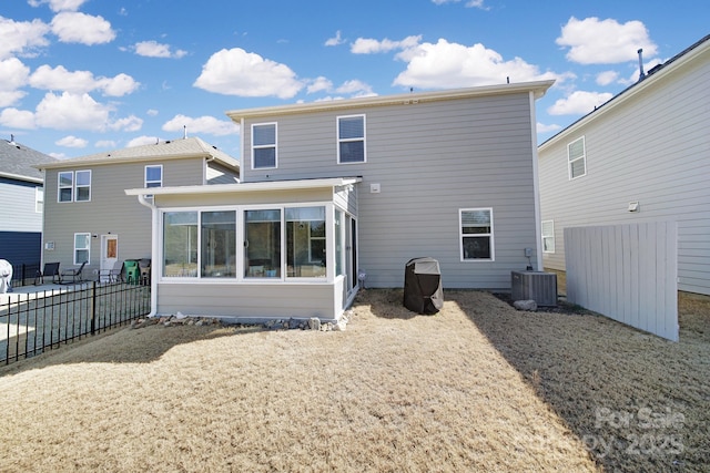 rear view of house with cooling unit, a sunroom, and fence