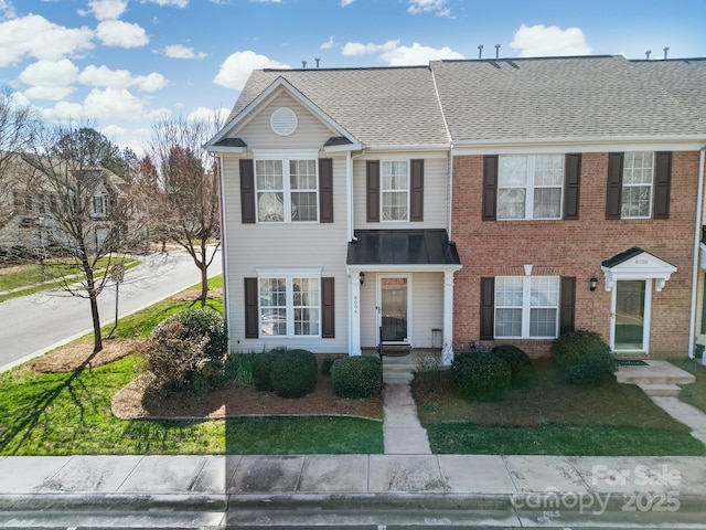 view of front of home featuring a shingled roof and brick siding