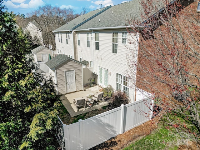 back of property featuring a patio area, a fenced backyard, a storage unit, and an outbuilding