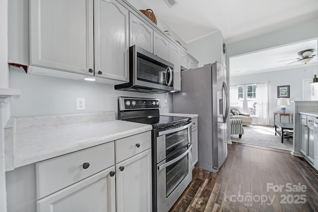 kitchen with a ceiling fan, appliances with stainless steel finishes, dark wood-style flooring, light countertops, and crown molding