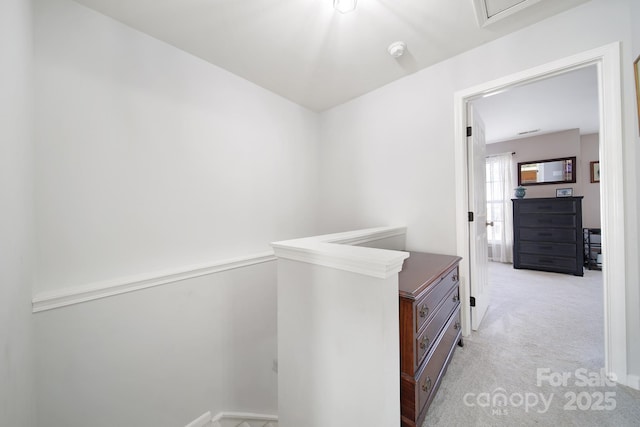 corridor with light colored carpet and an upstairs landing