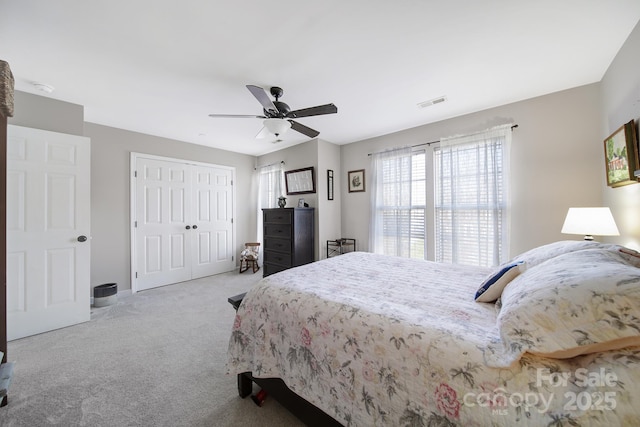 bedroom with light carpet, a closet, visible vents, and a ceiling fan