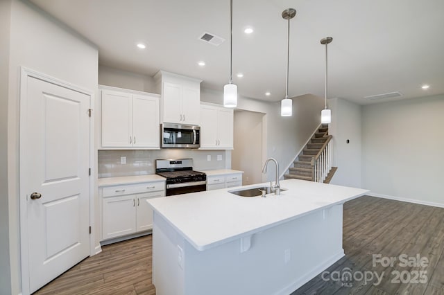2656 Tillman St, Monroe, NC 28112 - kitchen with stainless steel appliances, a sink, dark wood-style floors, a center island with sink, and white cabinets
