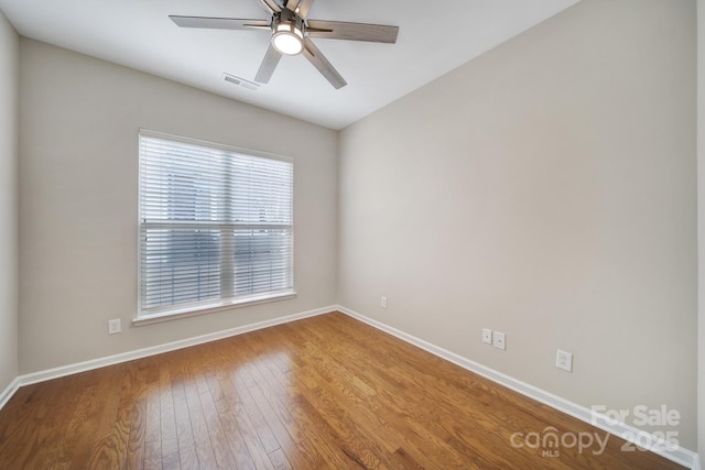 spare room featuring visible vents, a ceiling fan, baseboards, and wood-type flooring