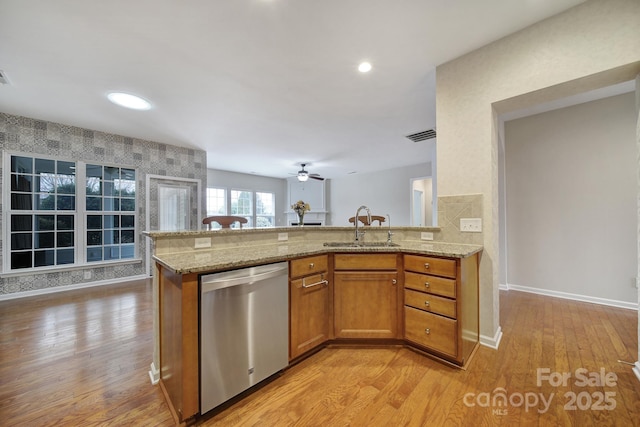 kitchen featuring brown cabinets, a sink, light wood finished floors, light stone countertops, and dishwasher