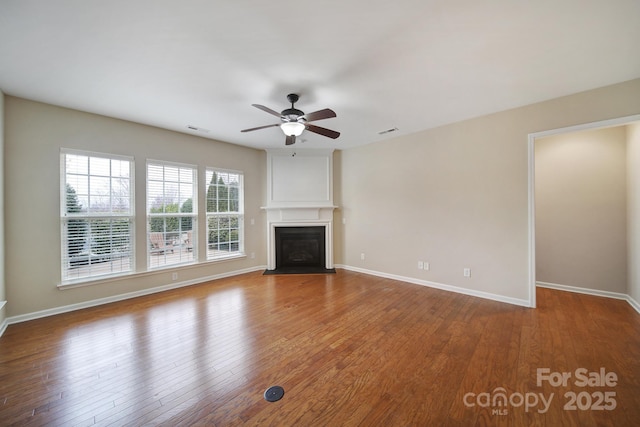 unfurnished living room with visible vents, baseboards, a fireplace, wood finished floors, and a ceiling fan