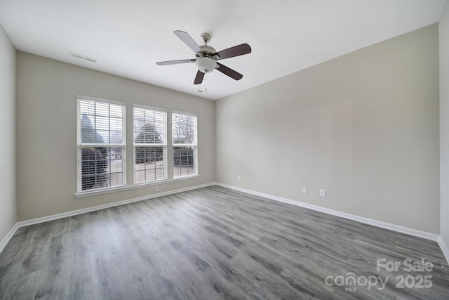 unfurnished room featuring a ceiling fan, wood finished floors, visible vents, and baseboards