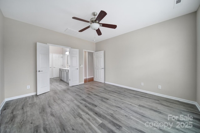 unfurnished bedroom featuring visible vents, connected bathroom, baseboards, wood finished floors, and a ceiling fan