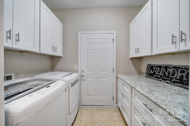 laundry area featuring washing machine and dryer, light tile patterned floors, and cabinet space