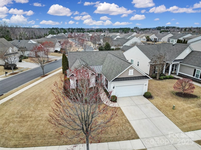 view of front of home featuring a front yard, a standing seam roof, concrete driveway, a residential view, and metal roof