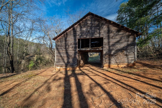 view of side of property featuring dirt driveway and an outdoor structure