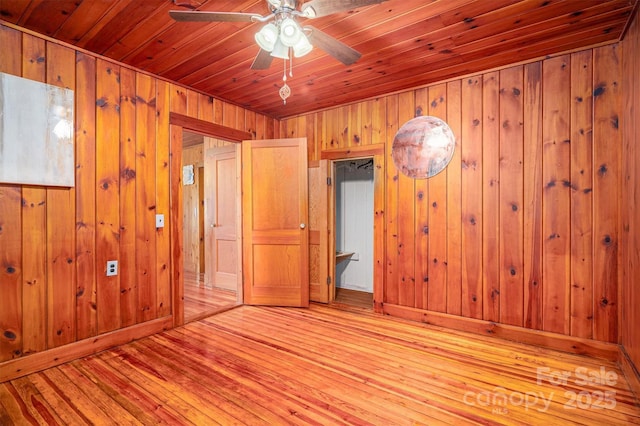 unfurnished bedroom with wooden walls, wood ceiling, and light wood-style flooring