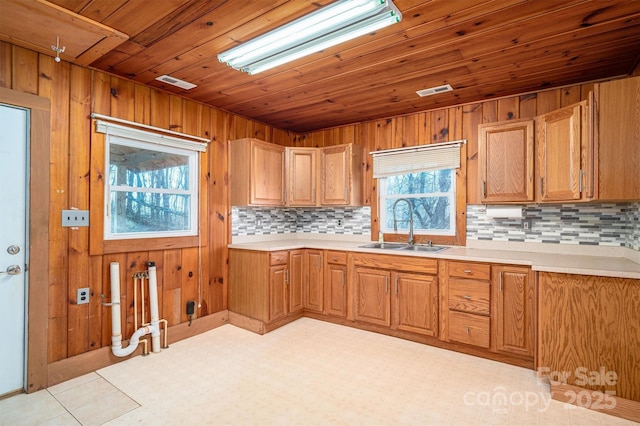 kitchen with brown cabinetry, light countertops, a sink, and visible vents