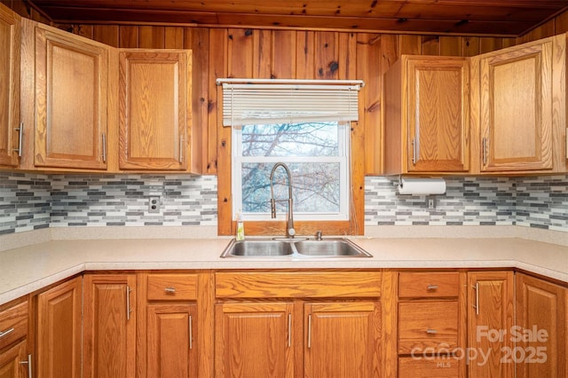 kitchen featuring brown cabinetry, decorative backsplash, light countertops, and a sink