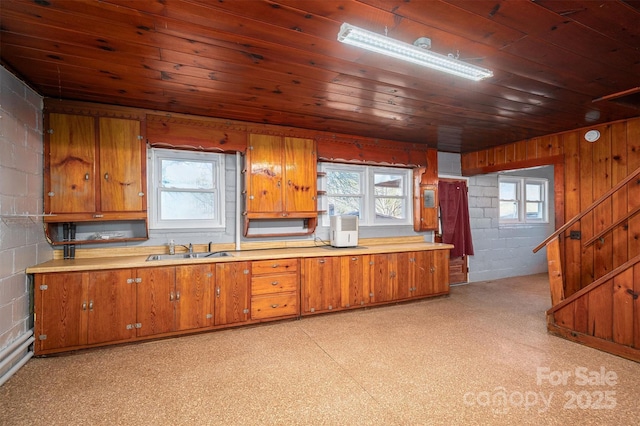 kitchen with brown cabinets, wooden ceiling, light countertops, and a sink