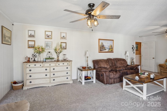 living room featuring a textured ceiling, carpet flooring, a ceiling fan, and crown molding