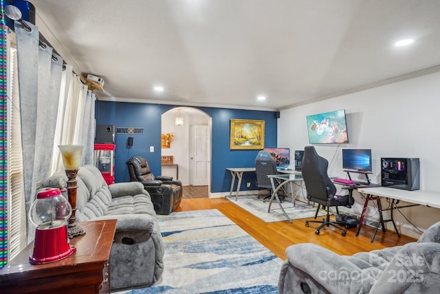 living area featuring baseboards, arched walkways, wood finished floors, crown molding, and recessed lighting