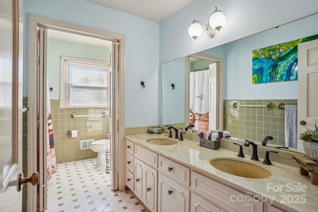 bathroom with visible vents, a sink, tile walls, and toilet