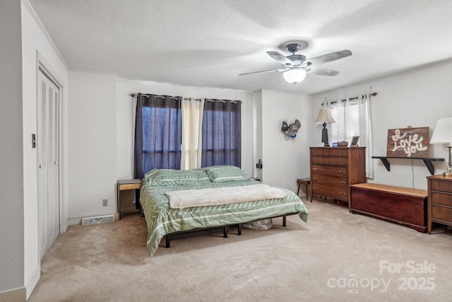 bedroom featuring a textured ceiling, visible vents, and light colored carpet