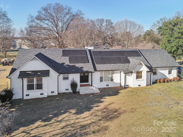 rear view of house with crawl space, a shingled roof, roof mounted solar panels, and a yard