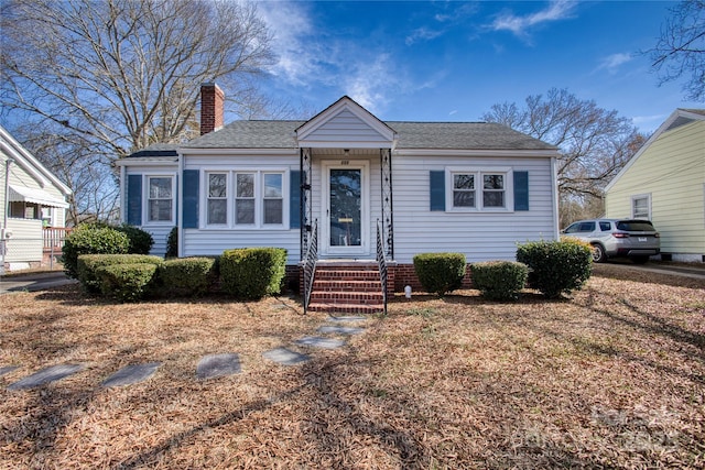 bungalow-style home featuring entry steps, a shingled roof, and a chimney