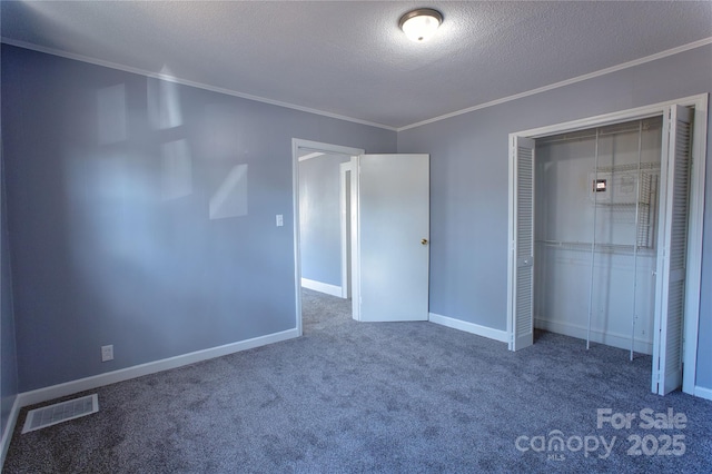 unfurnished bedroom featuring baseboards, visible vents, crown molding, carpet floors, and a closet
