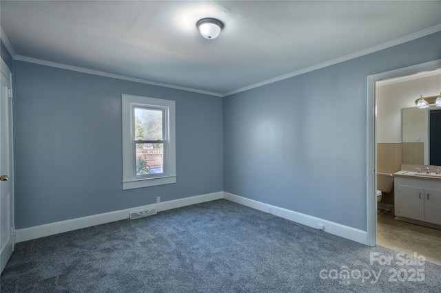 unfurnished bedroom with baseboards, visible vents, crown molding, carpet floors, and a sink