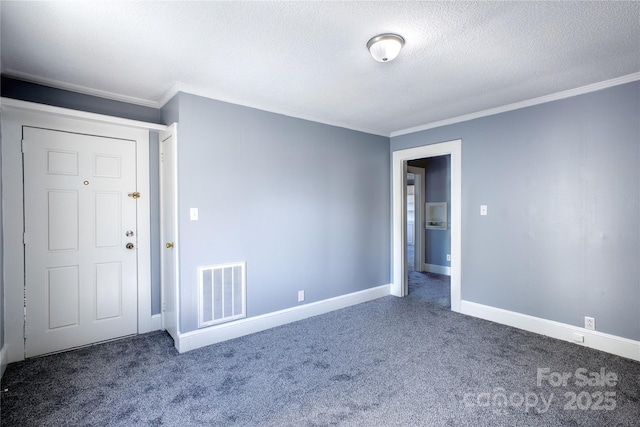 spare room with a textured ceiling, dark colored carpet, visible vents, and baseboards