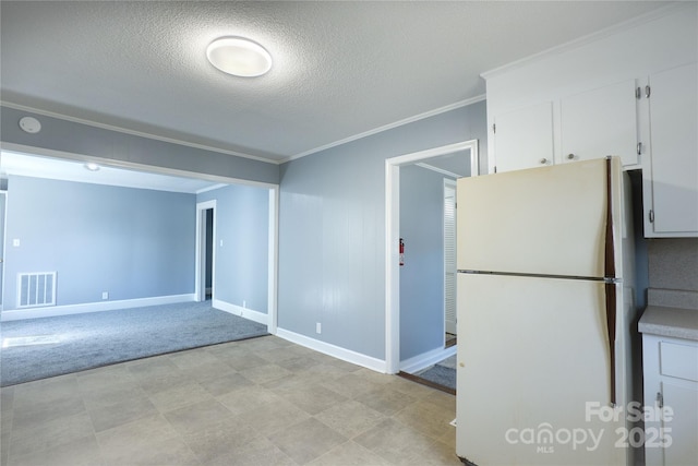 kitchen with crown molding, visible vents, freestanding refrigerator, white cabinets, and a textured ceiling
