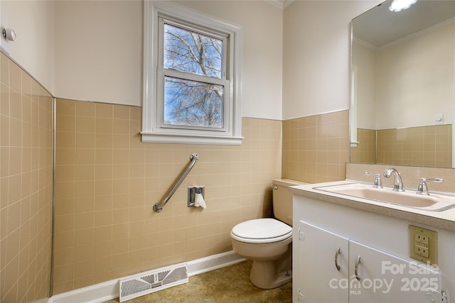 bathroom featuring visible vents, toilet, a wainscoted wall, vanity, and tile walls