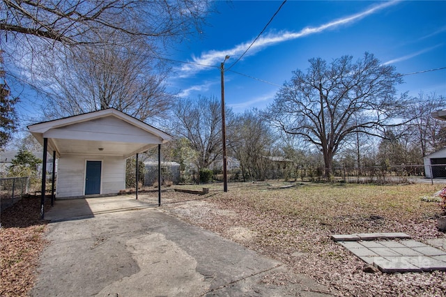 view of yard with a carport, fence, and concrete driveway