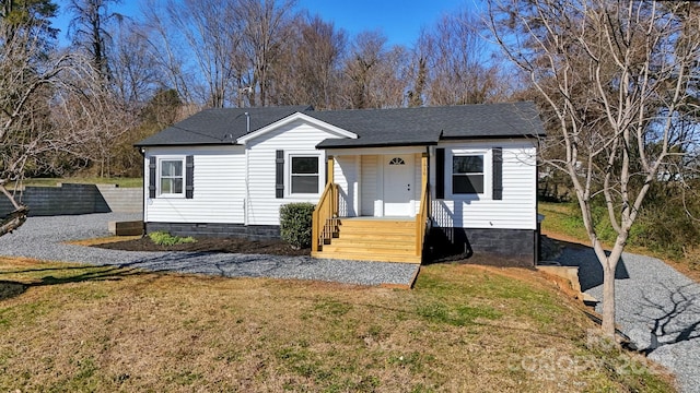 view of front of home with roof with shingles and a front lawn