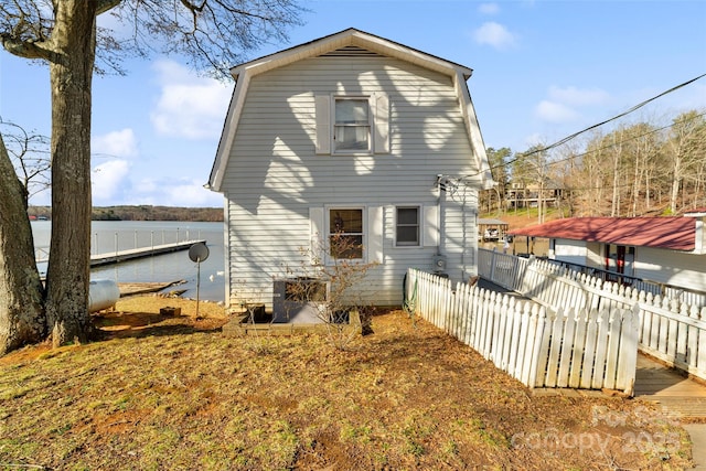 back of house featuring a water view, fence, and a gambrel roof