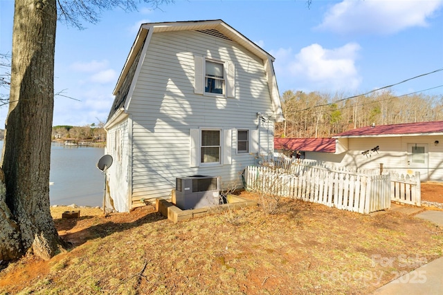 back of house with a water view, fence, and central air condition unit