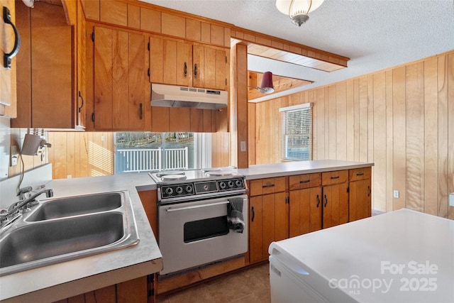 kitchen featuring light countertops, electric range, brown cabinets, and under cabinet range hood