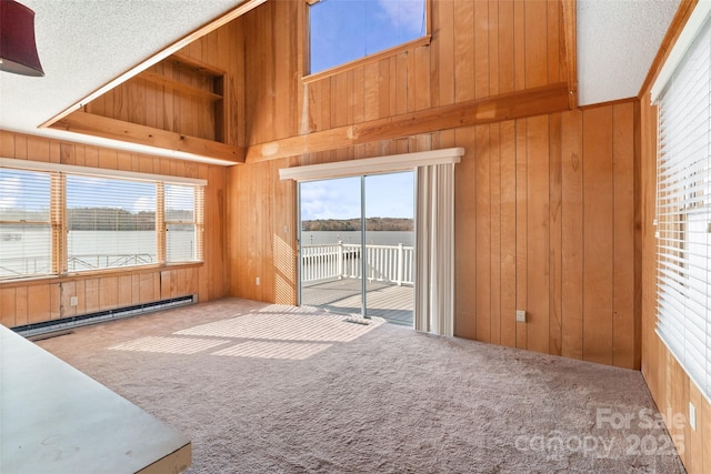 unfurnished living room featuring a baseboard radiator, a water view, carpet flooring, wood walls, and a textured ceiling